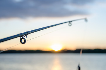 Image showing fishing rod with lure at sunset over a lake