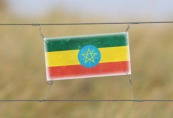 Image showing Border fence - Old plastic sign with a flag