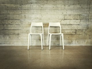 Image showing White chairs near concrete wall