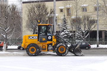 Image showing The yellow bulldozer cleans snow on city streets.