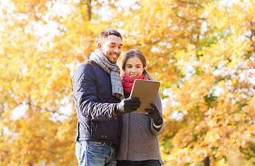 Image showing smiling couple with tablet pc in autumn park