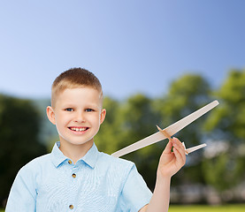 Image showing smiling little boy holding a wooden airplane model