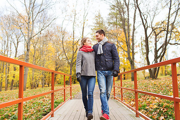 Image showing smiling couple hugging on bridge in autumn park