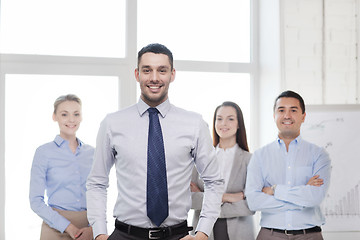 Image showing smiling businessman in office with team on back