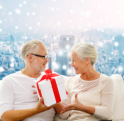 Image showing happy senior couple with gift box at home