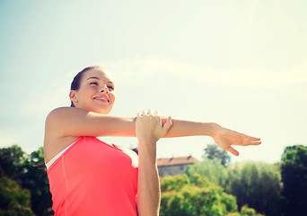 Image showing smiling woman stretching outdoors