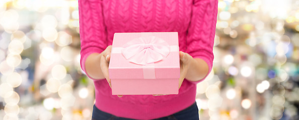 Image showing close up of woman in pink sweater holding gift box