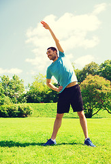 Image showing smiling man stretching outdoors