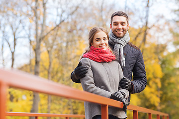 Image showing smiling couple hugging on bridge in autumn park