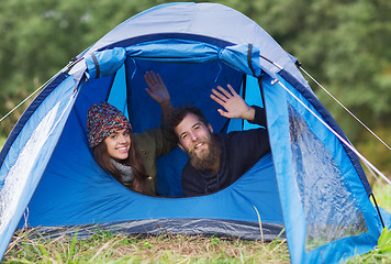 Image showing smiling couple of tourists looking out from tent