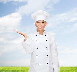 Image showing smiling female chef holding something on hand