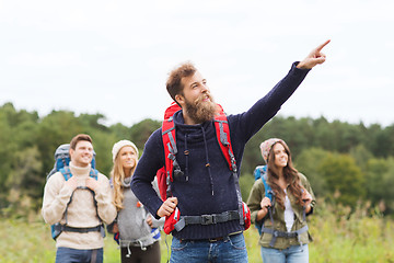 Image showing smiling hikers with backpacks pointing finger