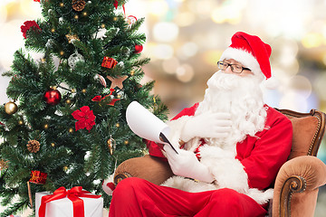 Image showing man in costume of santa claus with notepad