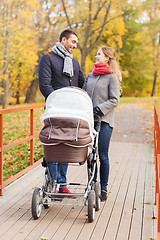 Image showing smiling couple with baby pram in autumn park