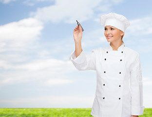 Image showing smiling female chef writing something on air