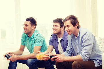 Image showing smiling friends playing video games at home