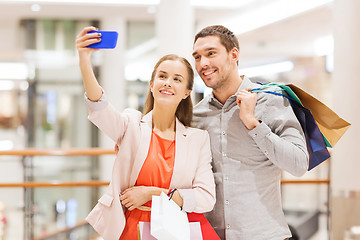 Image showing happy couple with smartphone taking selfie in mall