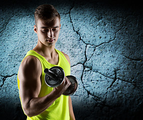 Image showing young man with dumbbell flexing biceps