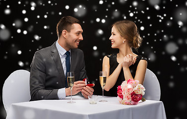 Image showing smiling couple with red gift box at restaurant