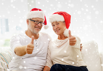 Image showing happy senior couple in santa helper hats at home