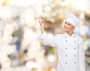 Image showing smiling female chef pointing finger to something