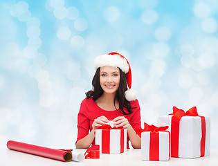Image showing smiling woman in santa helper hats packing gifts