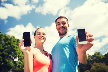 Image showing two smiling people with smartphones outdoors