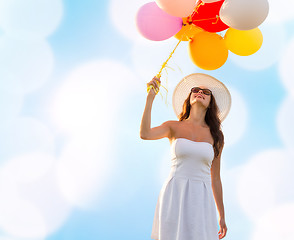 Image showing smiling young woman in sunglasses with balloons