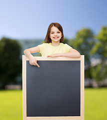 Image showing happy little girl pointing finger to blackboard