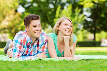 Image showing smiling couple lying on blanket in park