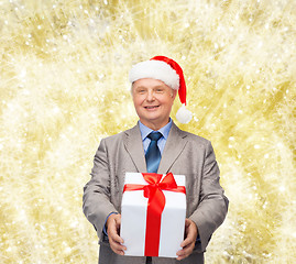 Image showing smiling man in suit and santa helper hat with gift