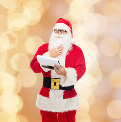 Image showing man in costume of santa claus with notepad