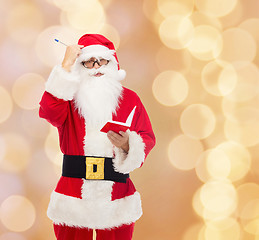 Image showing man in costume of santa claus with notepad