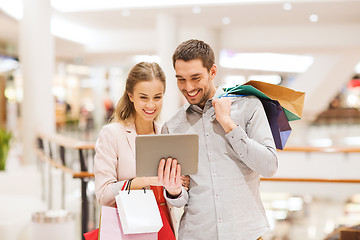 Image showing couple with tablet pc and shopping bags in mall