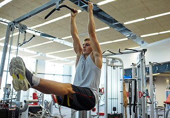 Image showing man flexing abdominal muscles on pull-up bar