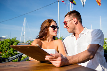 Image showing smiling couple with menu at cafe