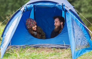 Image showing smiling couple of tourists looking out from tent