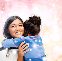 Image showing smiling little girl and mother hugging indoors