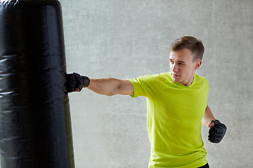 Image showing young man in gloves boxing with punching bag