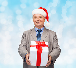 Image showing smiling man in suit and santa helper hat with gift