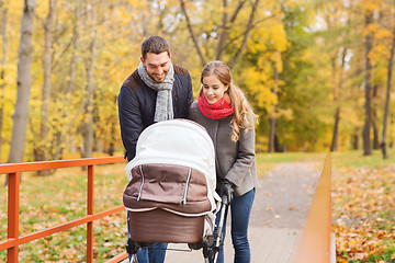 Image showing smiling couple with baby pram in autumn park