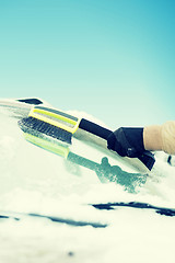 Image showing man cleaning snow from car windshield with brush