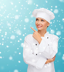 Image showing smiling female chef dreaming pointing finger up