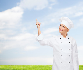 Image showing smiling female chef pointing finger to something