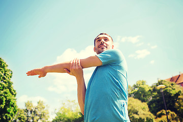 Image showing smiling man stretching outdoors