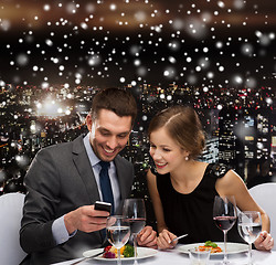Image showing smiling couple with smartphone at restaurant
