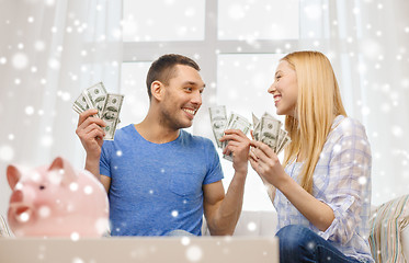 Image showing happy couple with money and piggybank at home