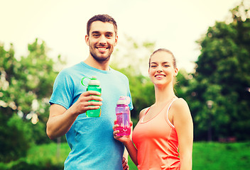 Image showing smiling couple with bottles of water outdoors