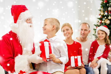 Image showing smiling family with santa claus and gifts at home