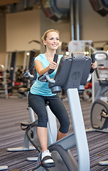 Image showing smiling woman exercising on exercise bike in gym